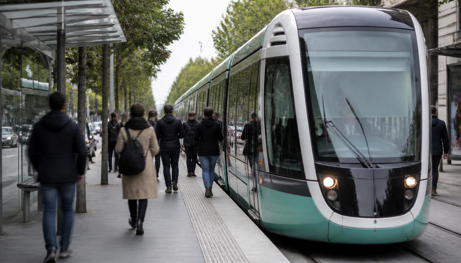 Light-rail streetcar at an urban platform beside a tree-lined street